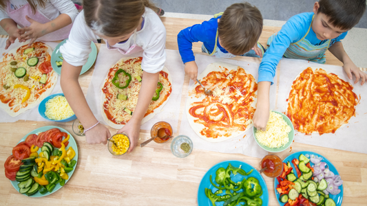 Kinder helfen beim Kochen und Backen mit. Kinder belegen Pizza und haben Spaß dabei